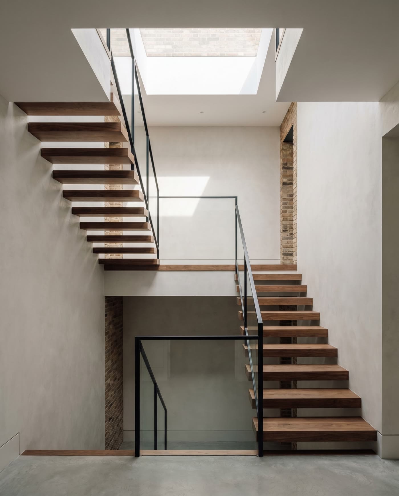 A floating oak staircase beneath a skylight